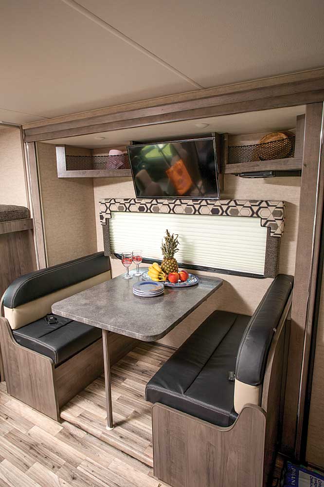 Handy open shelving and a 32-inch HDTV are mounted over the dinette that’s housed in the curbside slideout. 