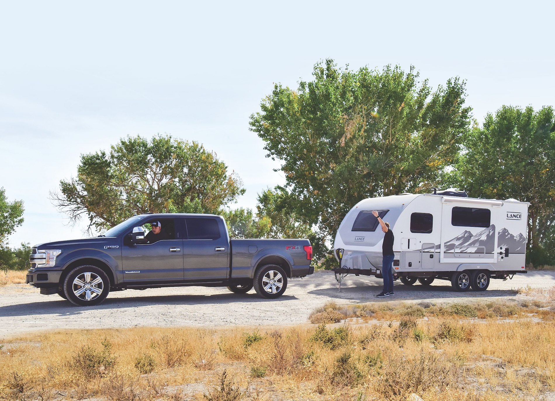 A truck backing up and hitching up to a travel trailer