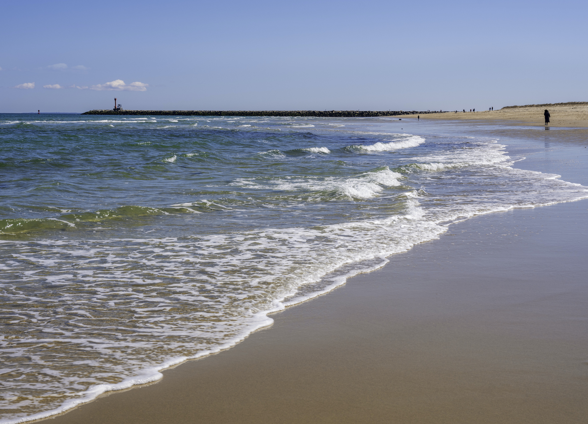 Pristine Scusset Beach seascape in Sagamore at the north end of the Cape Cod Canal. In distance, there are small numbers of people walking and resting.