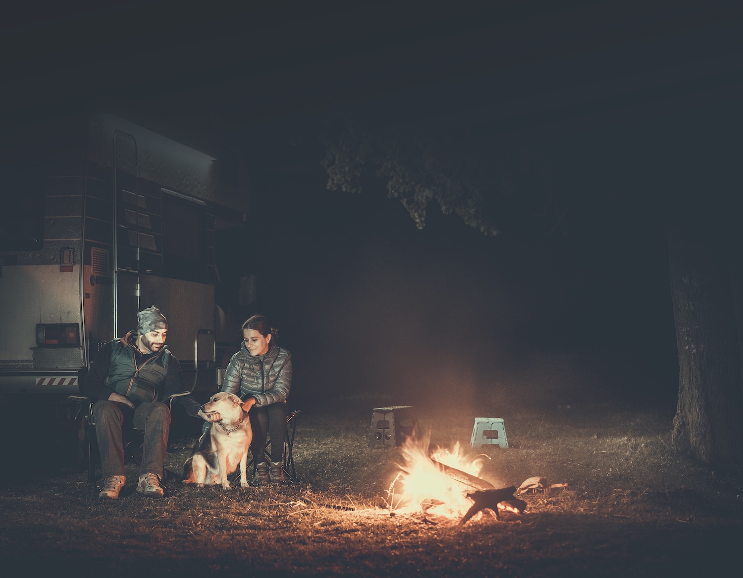 Couple on vacation near campfire and motorhome