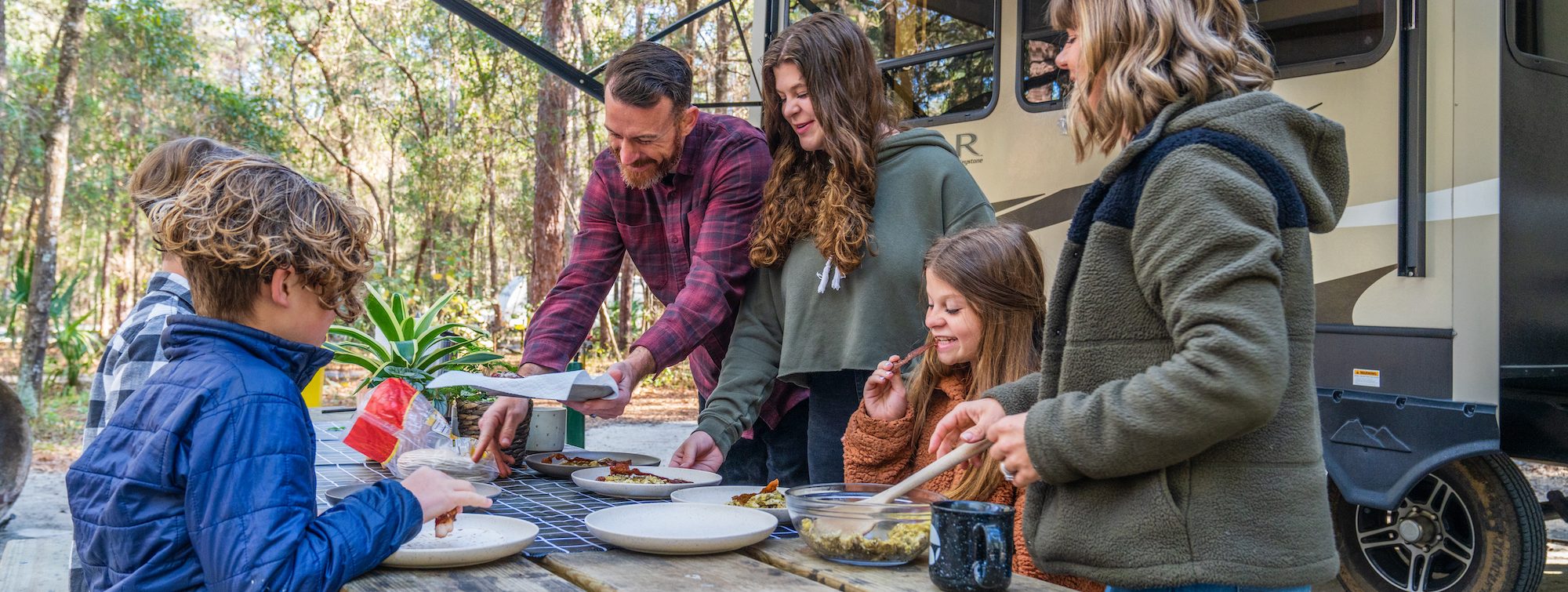 family eating breakfast outside of their RV