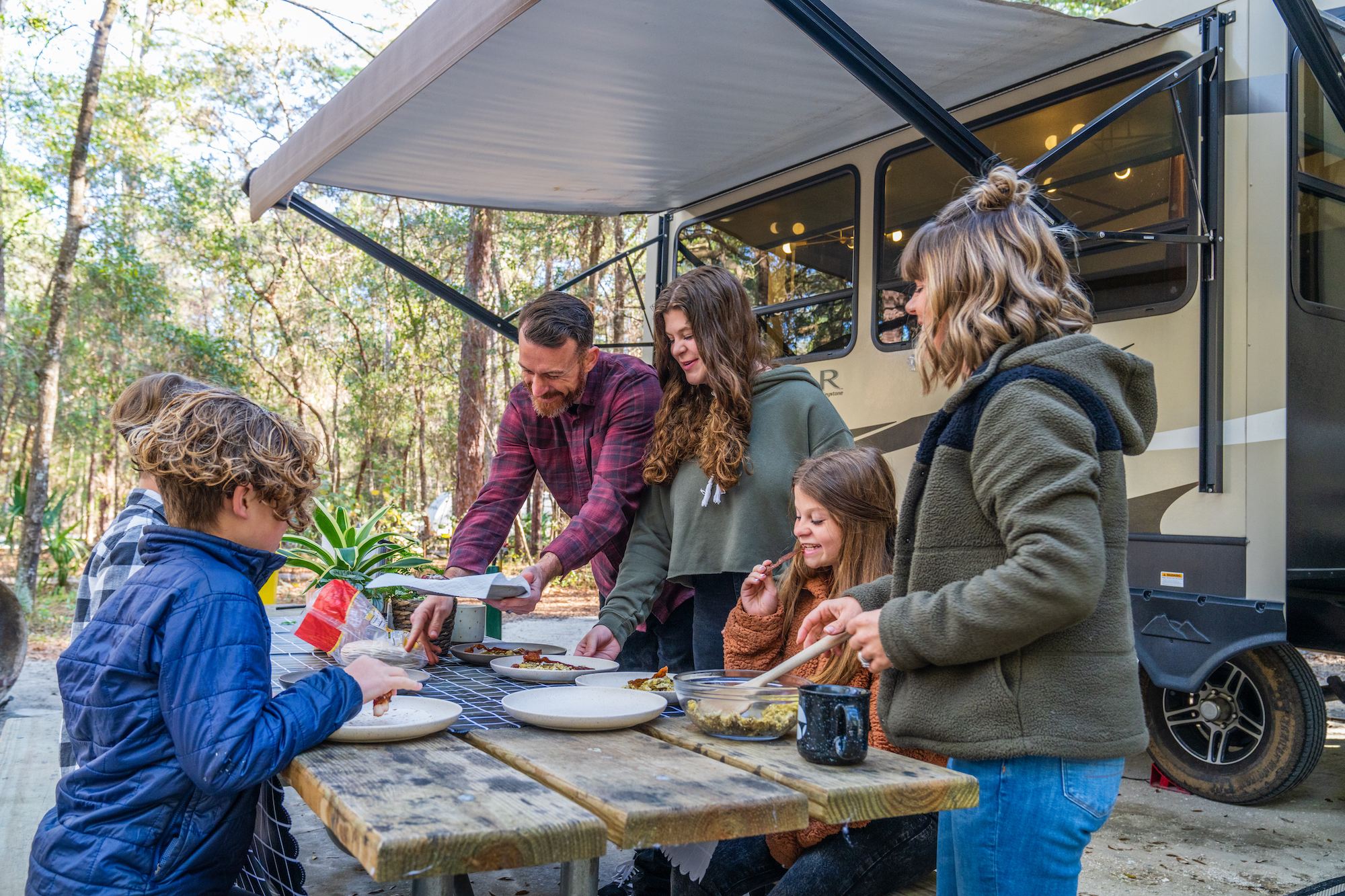 family eating breakfast outside of their RV
