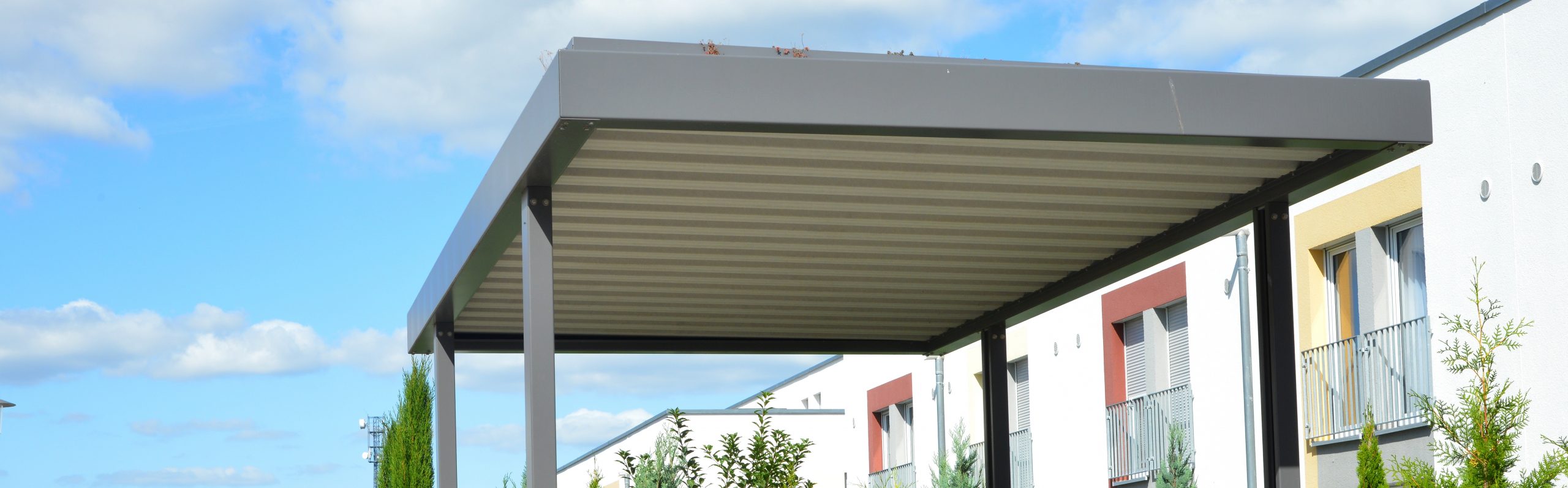 New Metal Carport with greened Roof in Front of a Multi Family residential Building