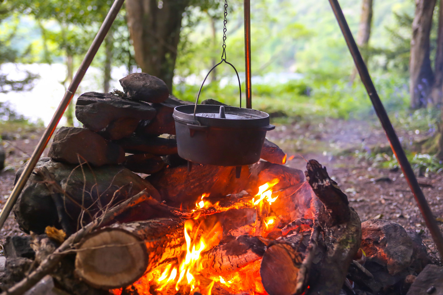 Cast iron pot cooks over open fire in a campsite