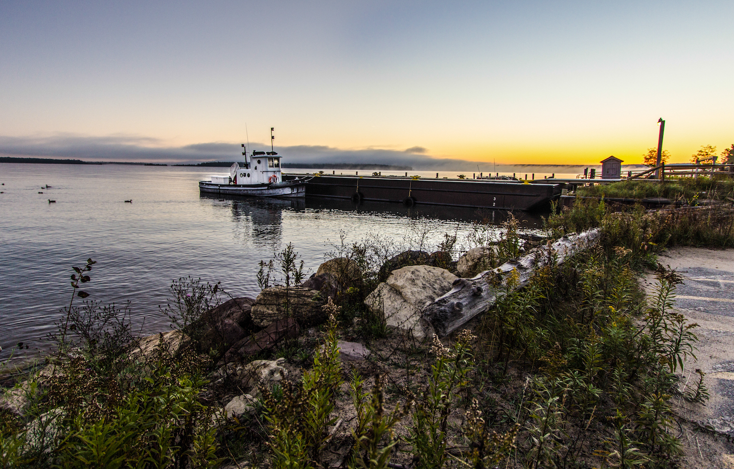 Lake Superior Sunrise. Small tugboat moored on a Lake Superior dock with a coastal sunrise in the background. Grand Island National Recreation Area. Munising, Michigan.