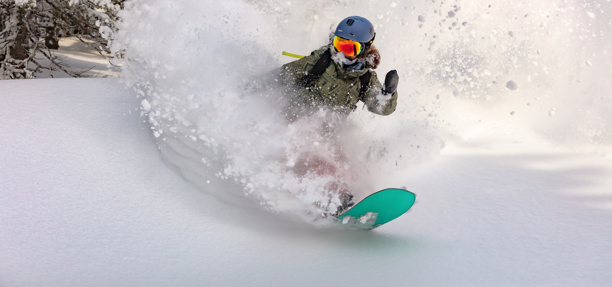 female snowboarder curved and brakes spraying loose deep snow on the freeride slope. downhill with snowboards in fresh snow. freeride world champion. swirls of snow in the air, in a bright mask