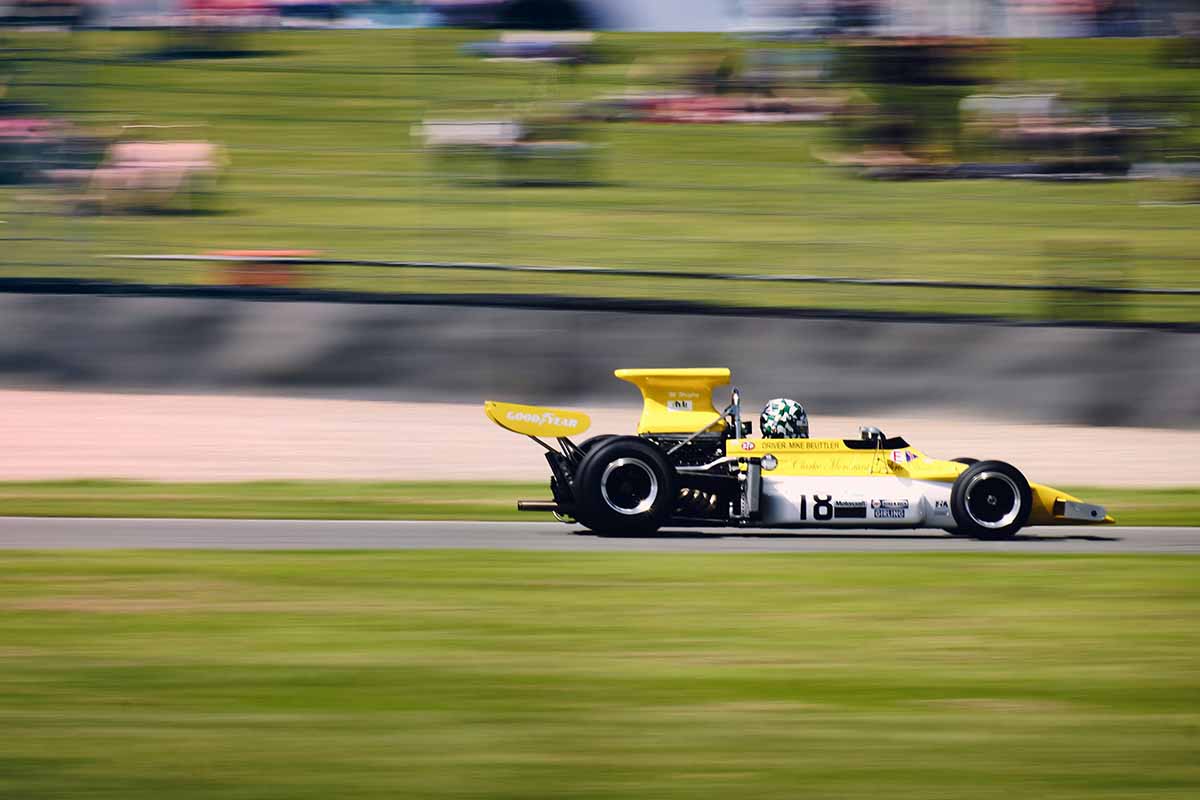Yellow formula one car careens around a track.
