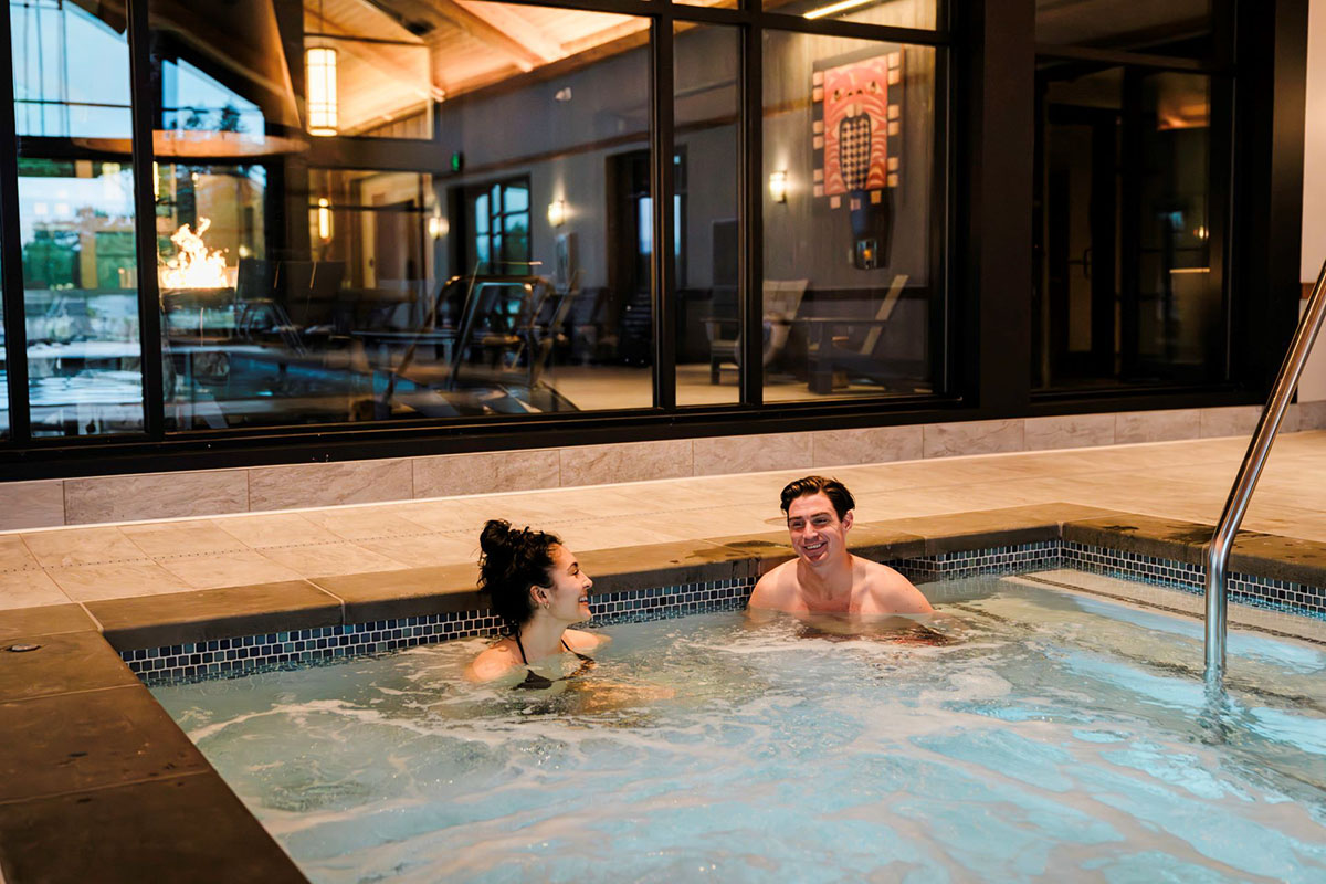 A couple relaxes in an indoor hot tub.