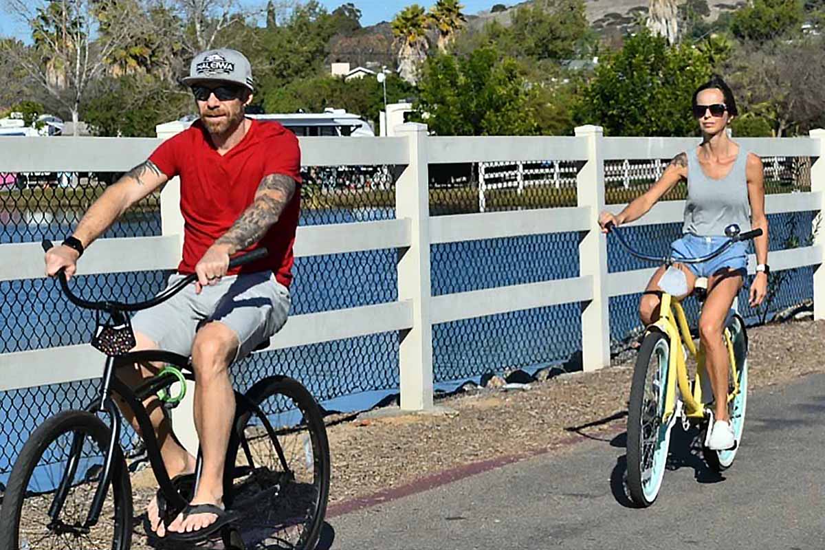 A couple biking close to water.