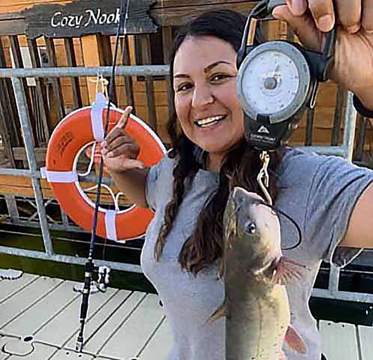 Woman showing off hefty fish that she caught.