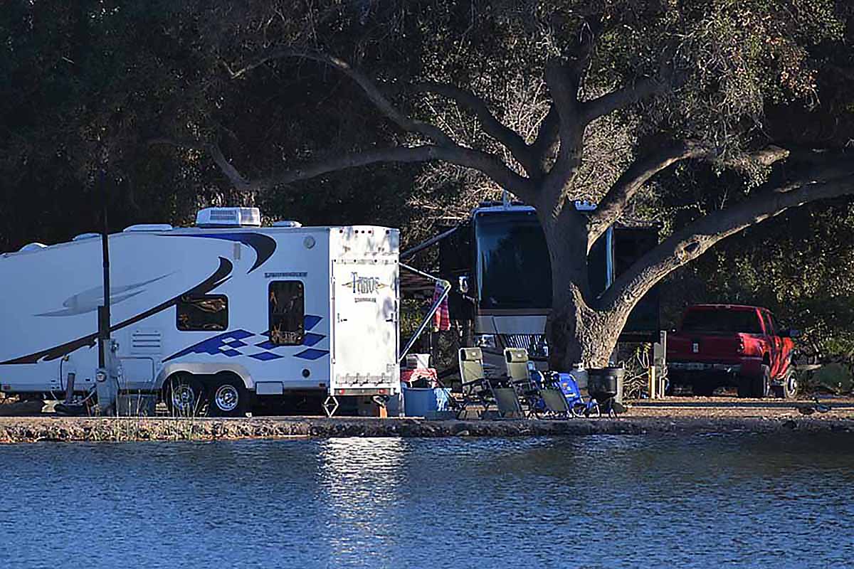 A travel trailer parked close to a lake.
