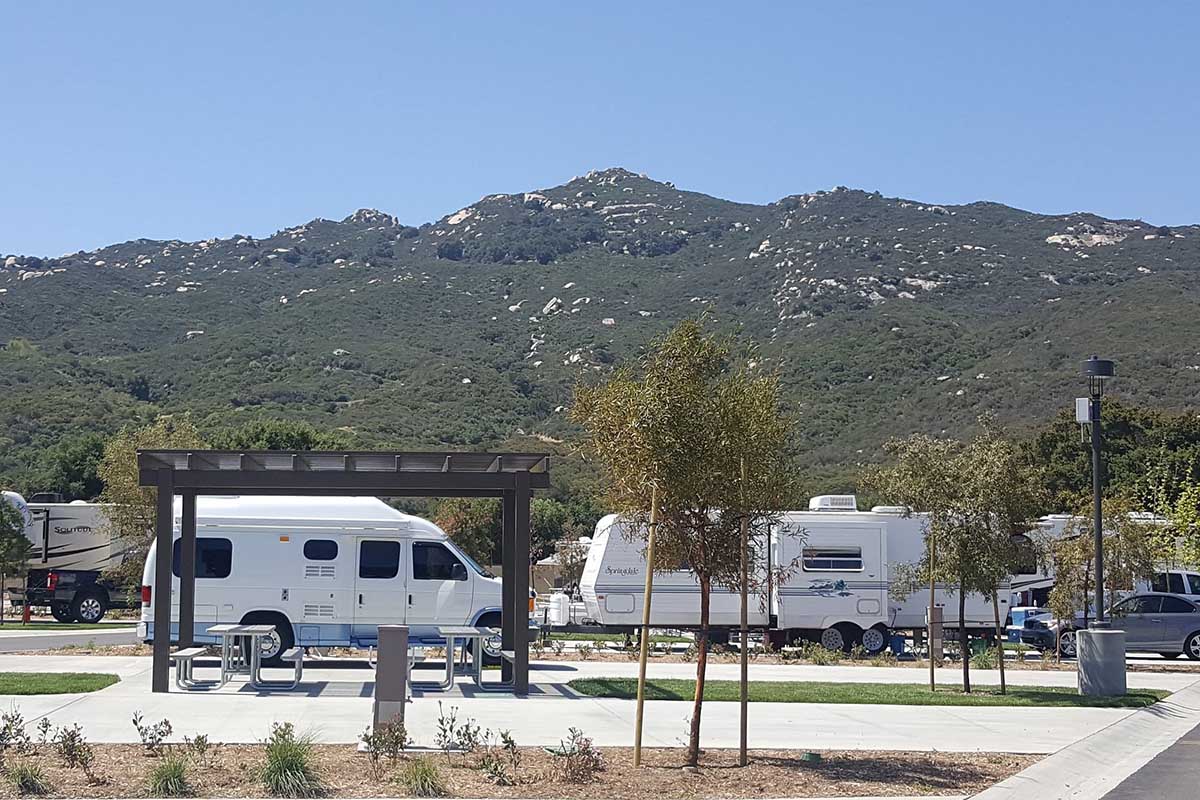 RV parked near gazebo and picnic benches with mountains in background.