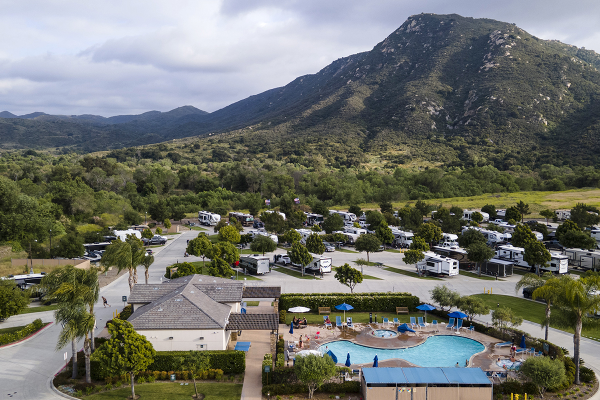 Motorhomes and travel trailers parked at the foot of a mountain.