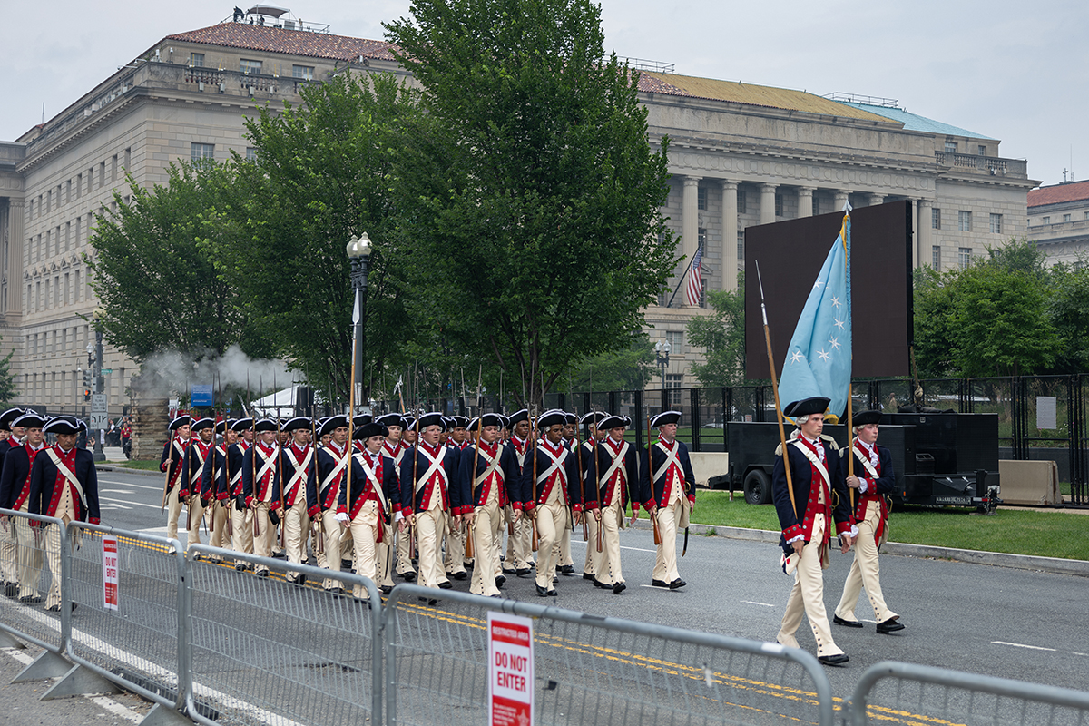 Soldiers in Revolutionary War uniforms marching.