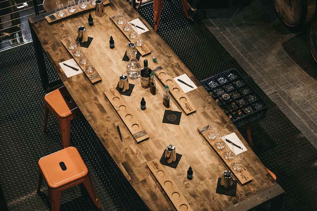 Birds eye view of table laden with bourbon and note pads.