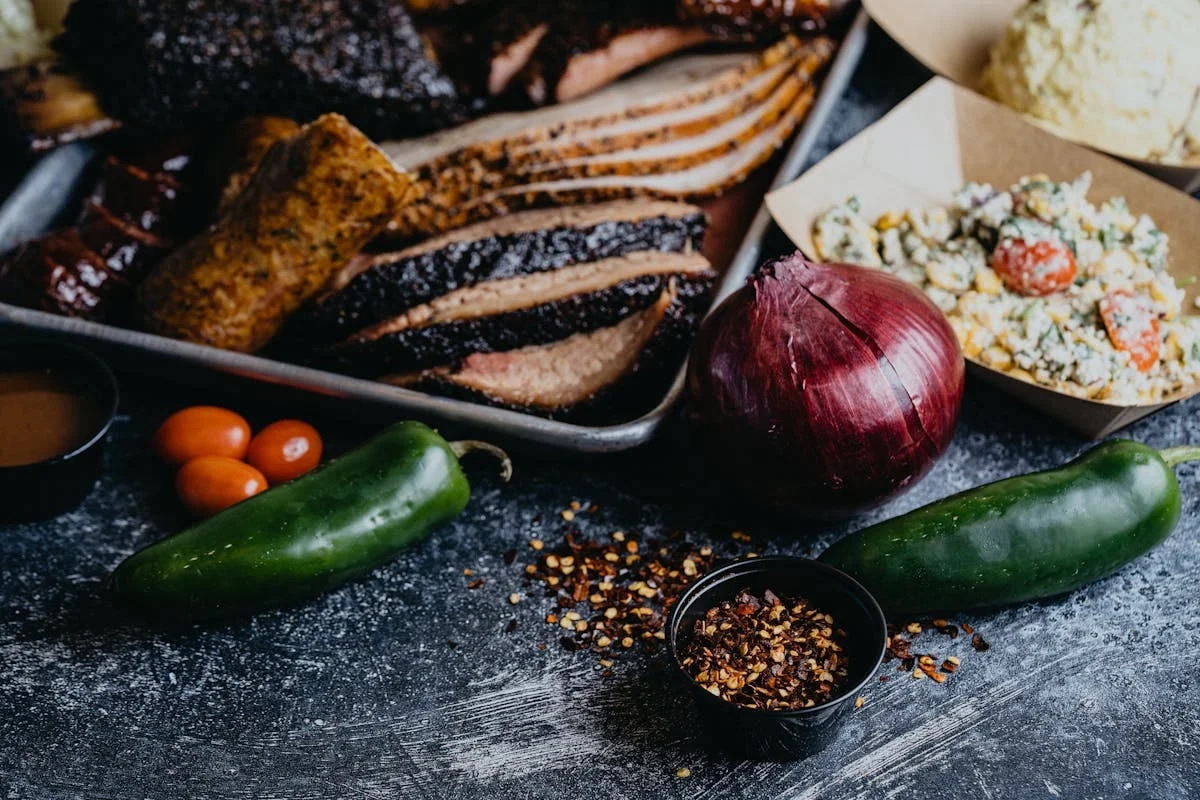 Cooked slices of beef surrounded by peppers and other veggies.