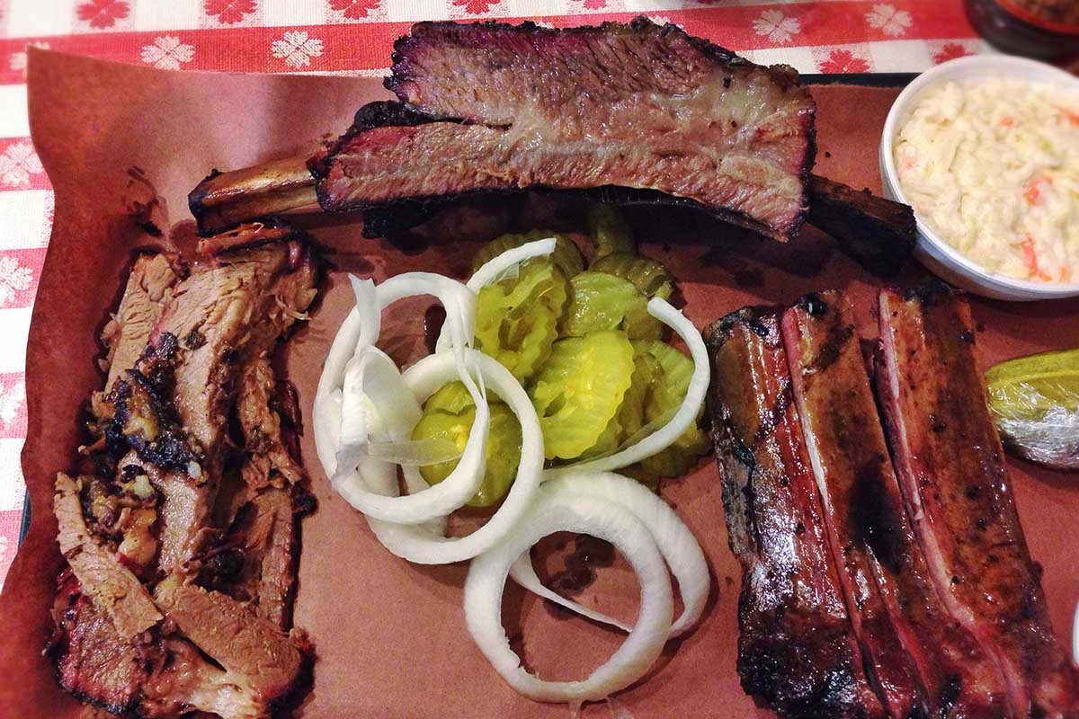 Cooked ribs with slaw, pickles, and onions.