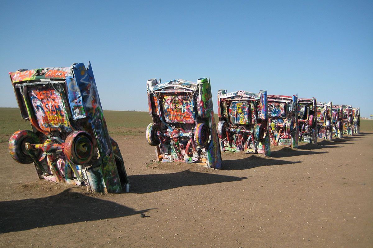 A row of cars half-bured in desert.