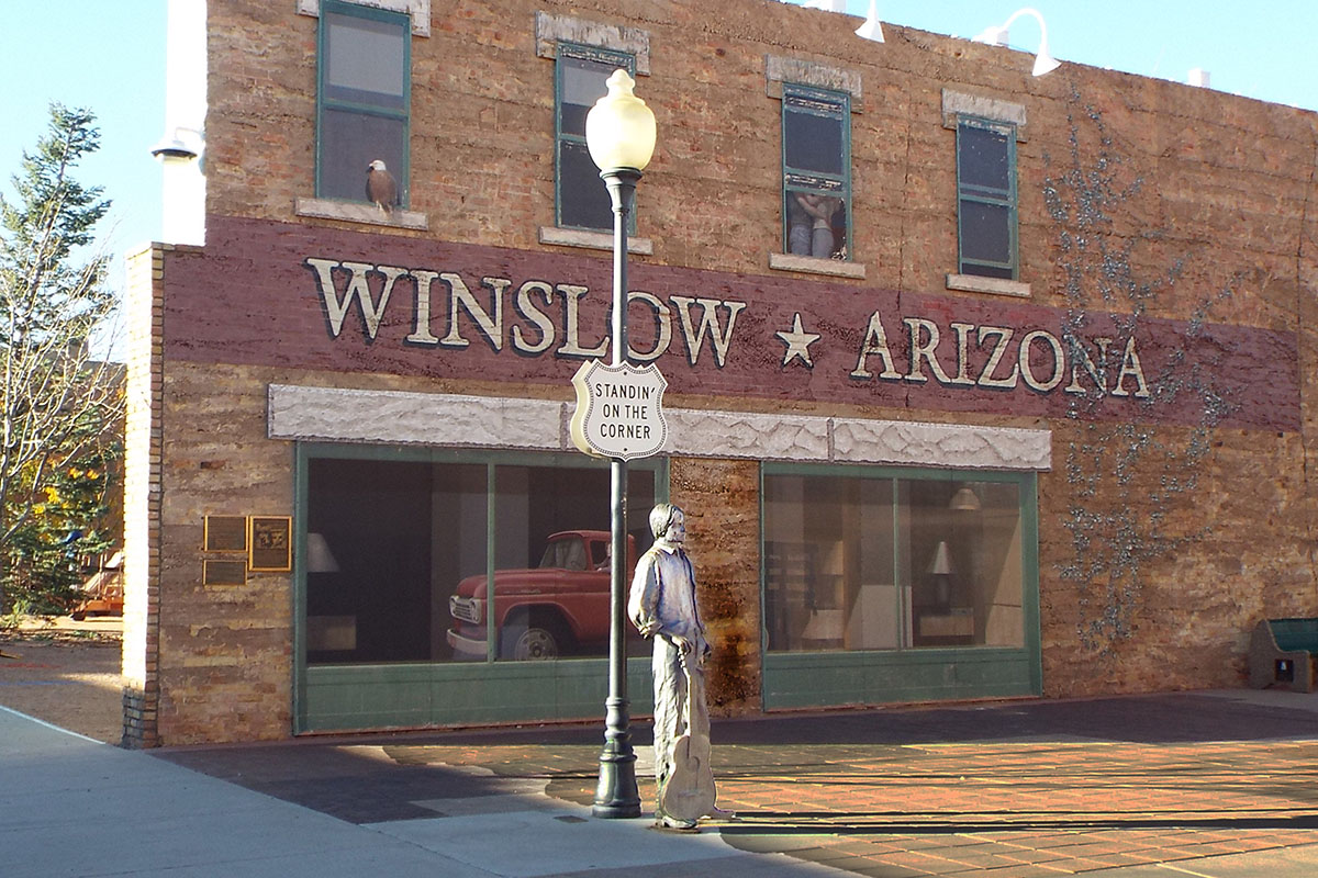 Statue of young man with guitar standing on a corner.