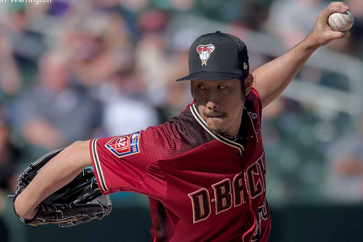 Man in red jersey throwing a baseball pitch.