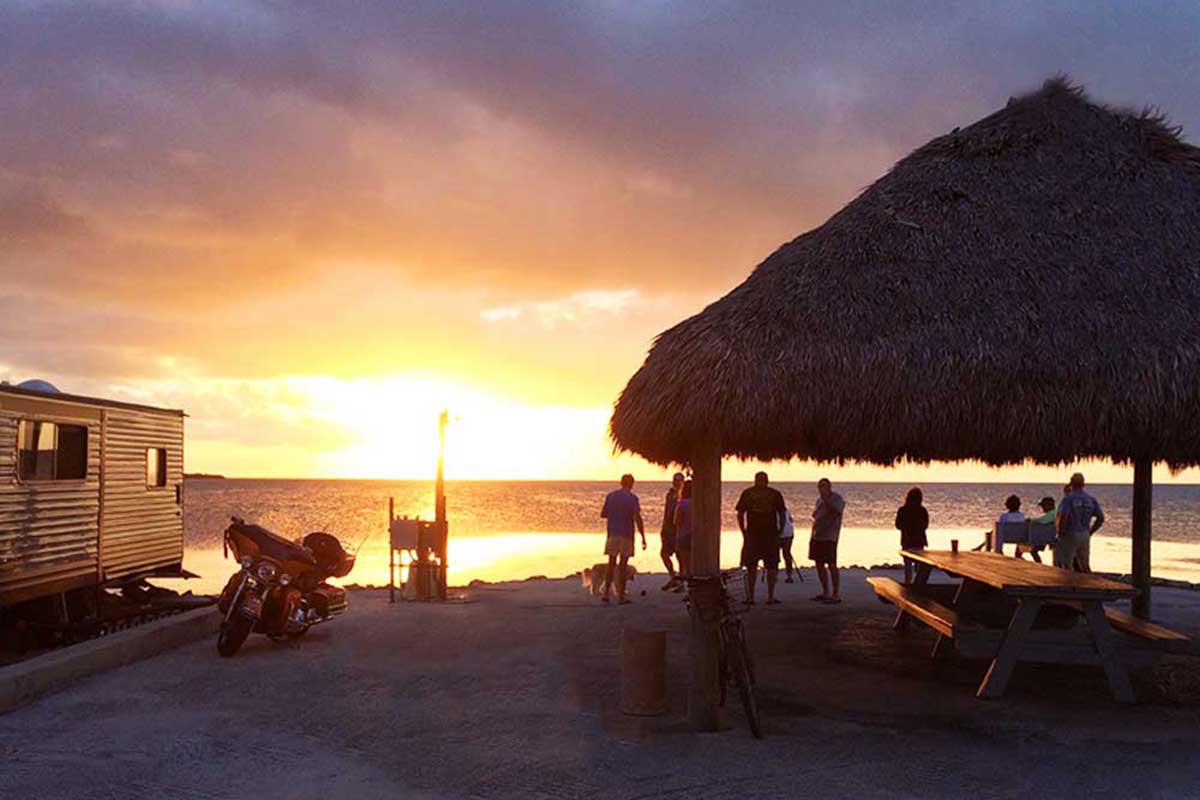 People lounging on the beach during sunset.