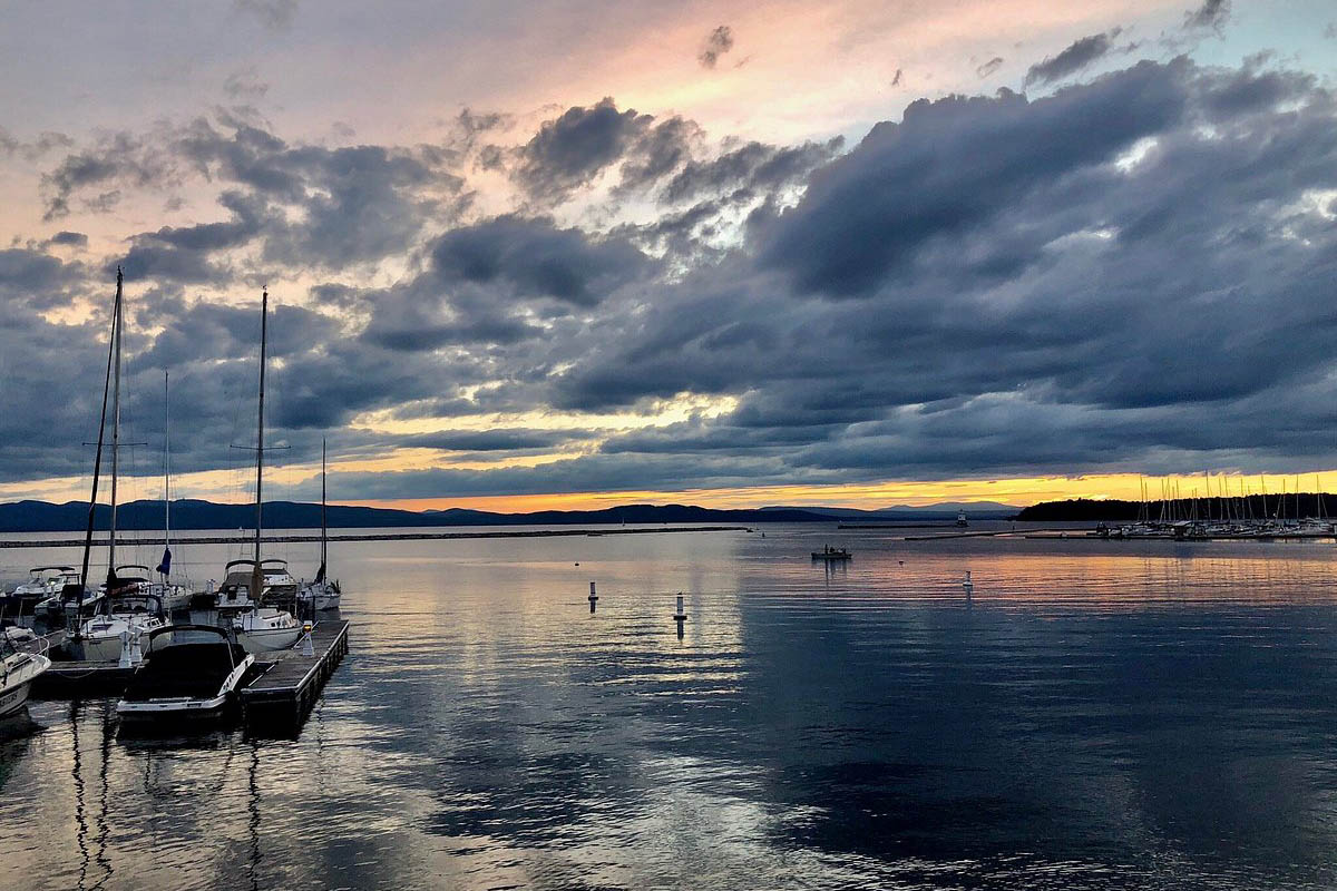 Boats docked on a placid bay at sunset.