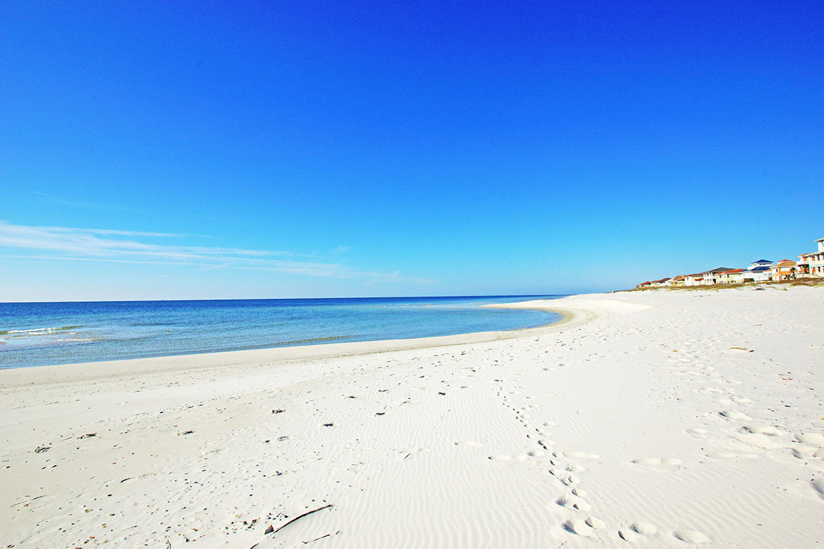 A white sand beach with some footsteps.