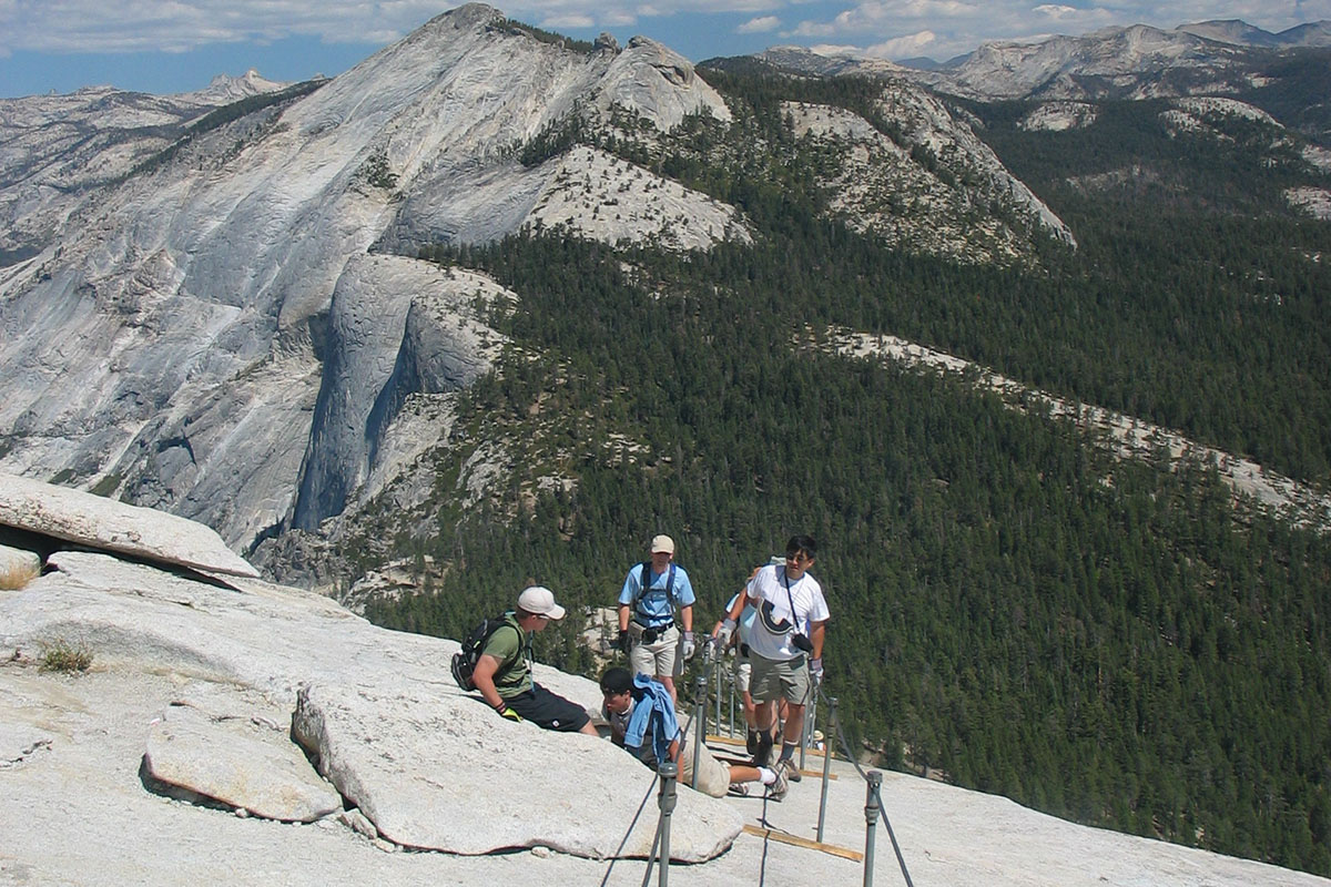 Young people ascending steep rocky slope.