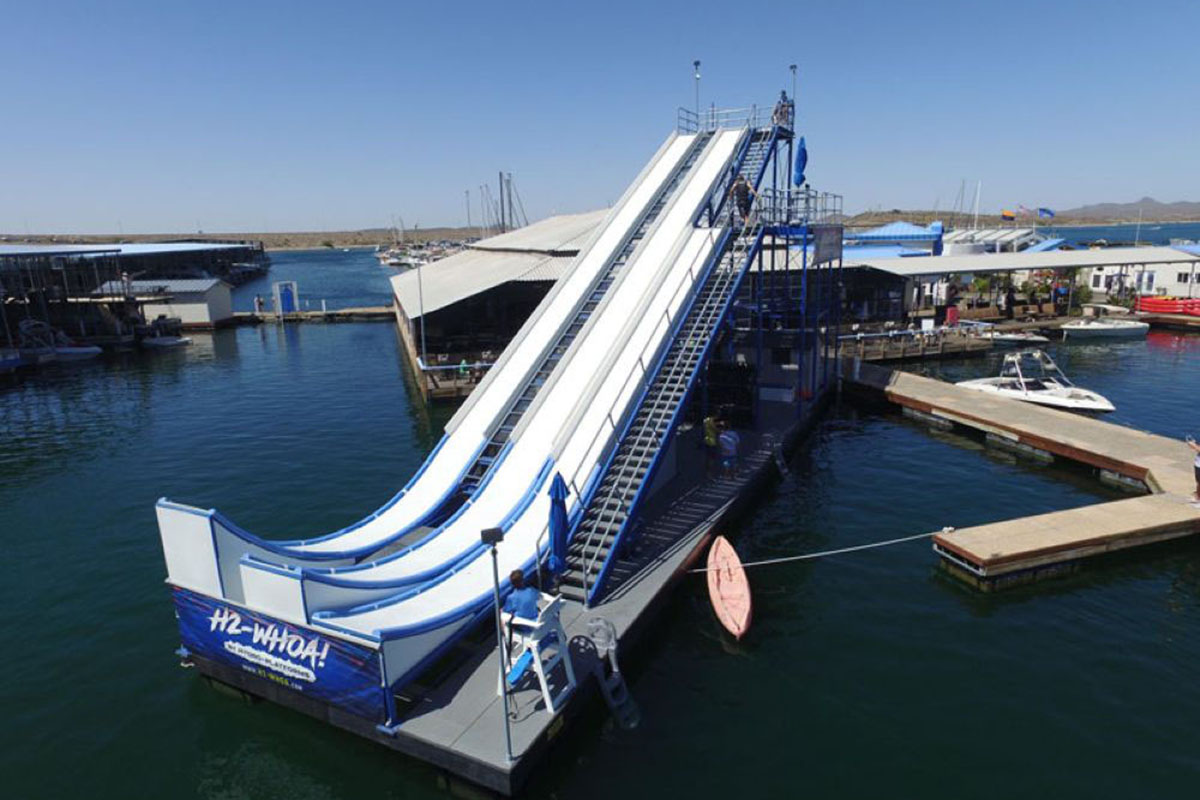 A long waterslide dipping into a lake.