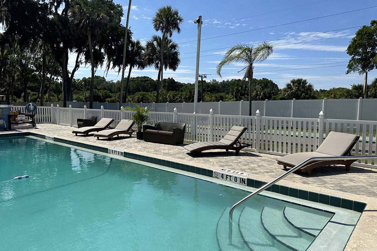 Pool edged with deck chairs.