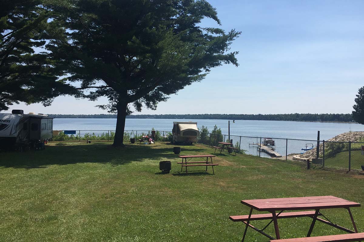 A picnic table on a grassy meadow overlooking a lake.